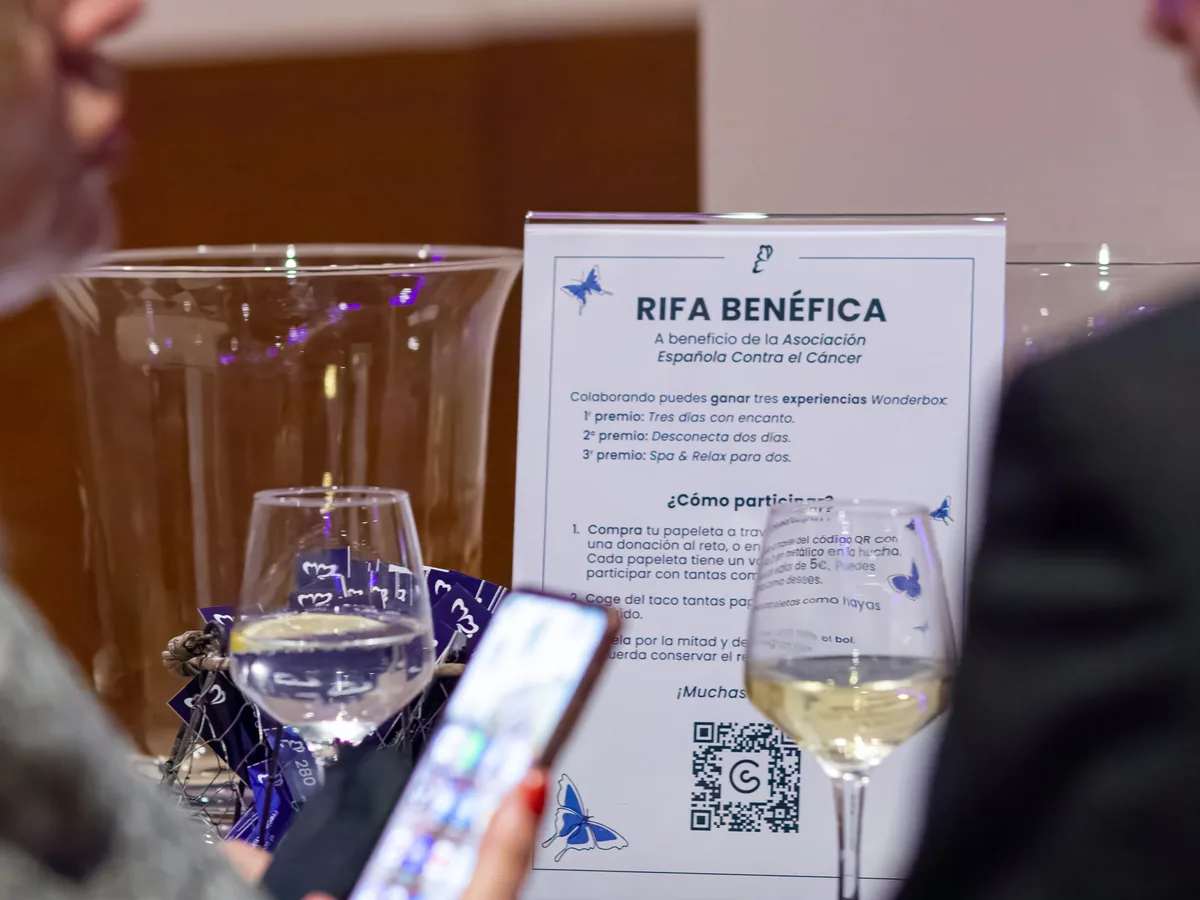 El cartel de la rifa benéfica junto a una copa de vino